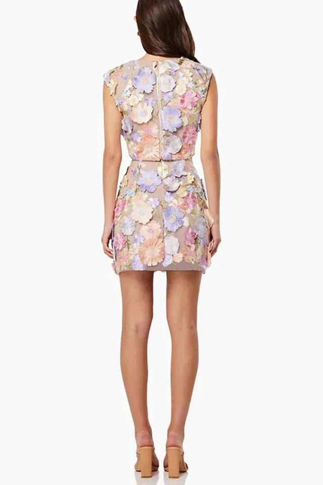Back view of a woman in a pastel floral embroidered crop top and mini skirt set