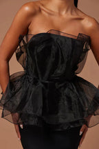 Close-up of black strapless formal dress with ruffled organza peplum