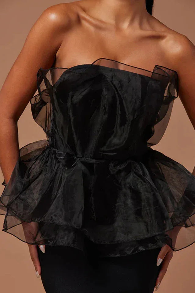 Close-up of black strapless formal dress with ruffled organza peplum