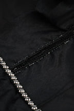 Close-up of beaded trim and sequin detail on black gown