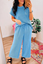 Woman posing in a blue ribbed knit top and drawstring waist pants