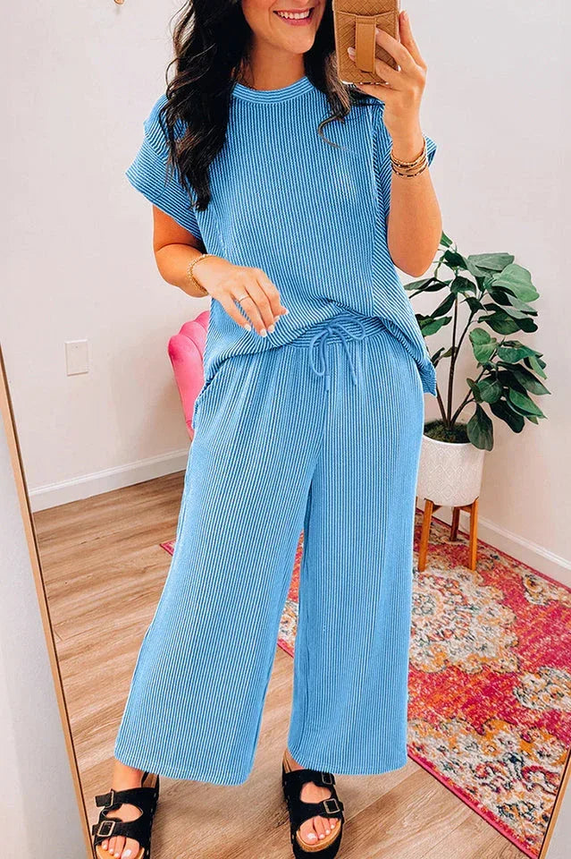 Woman posing in a blue ribbed knit top and drawstring waist pants
