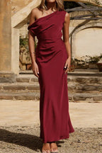 Full-body shot of a woman in a burgundy satin one-shoulder gown.