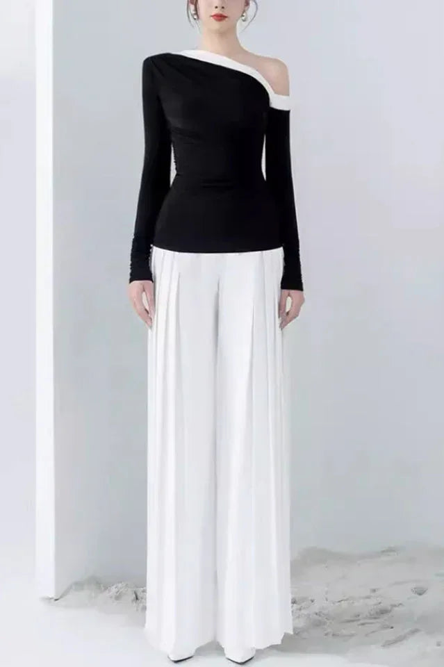 Woman wearing a black asymmetrical long-sleeve top and white wide-leg pleated pants. Main image