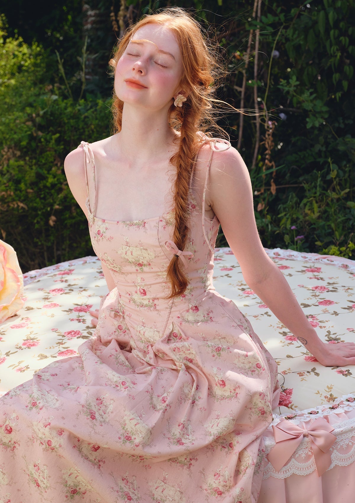 Back view of a pink floral print midi dress with spaghetti straps, a square neckline, and lace-up back detail.