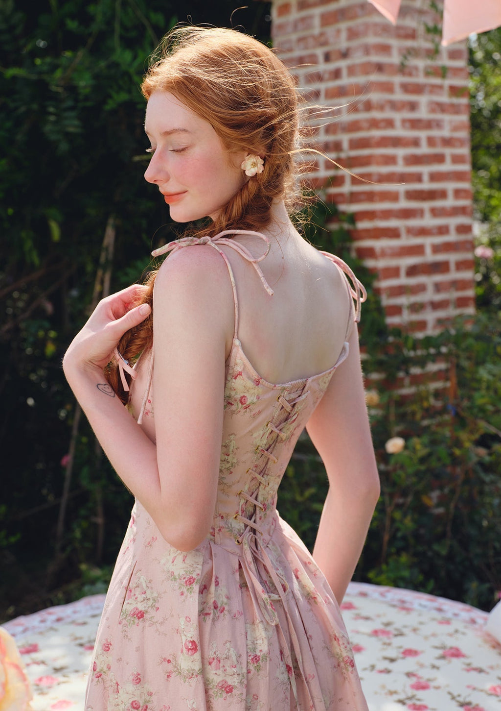 Full shot of a pink floral print midi dress with a pleated skirt.