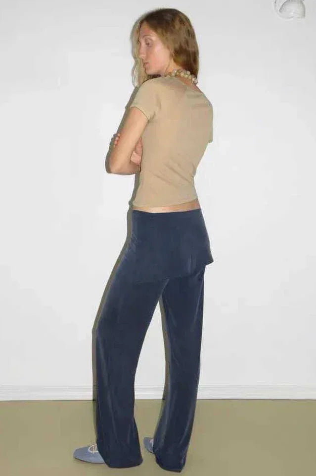 Back view of a woman wearing a tan short sleeve mock neck top and navy velour wide leg pants.