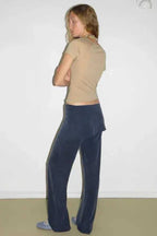 Back view of a woman wearing a tan short sleeve mock neck top and navy velour wide leg pants.