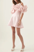 Full body shot of a woman in a light pink party dress with floral accents, styled with white open-toe heels.