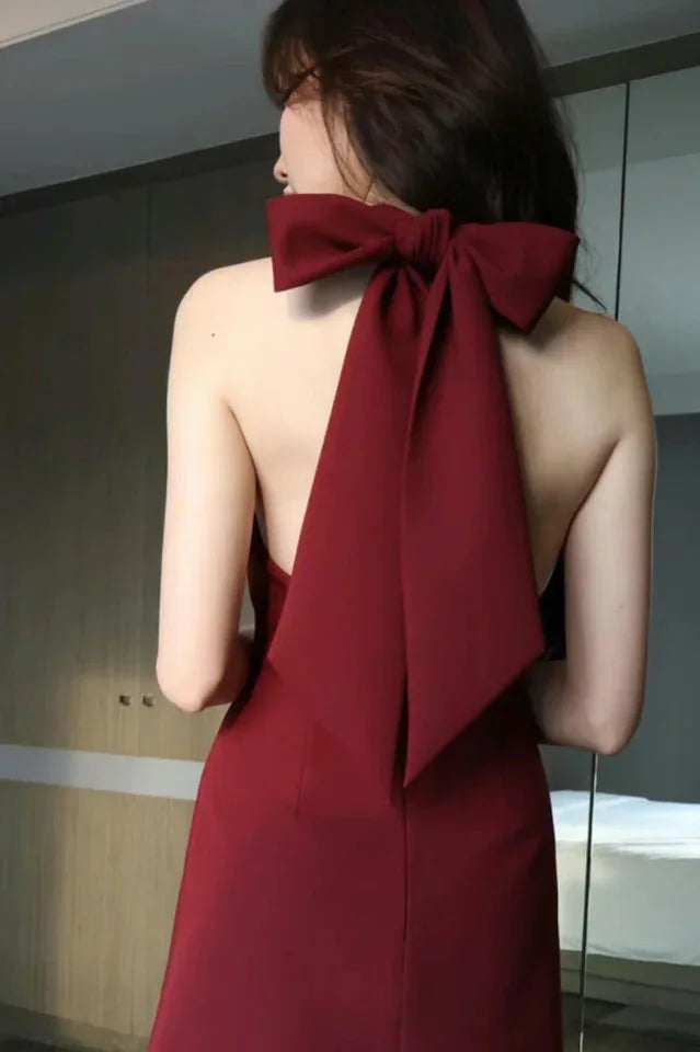 Rear view of a red mini dress featuring an open back with a large bow tie