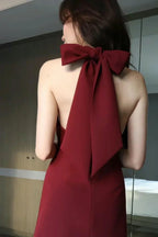 Rear view of a red mini dress featuring an open back with a large bow tie