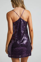 back view of a woman in a purple sequin mini dress with criss-cross straps