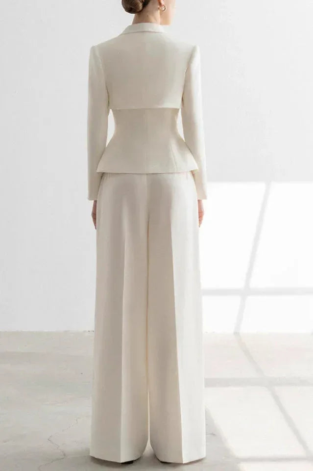 Woman wearing a white tailored suit set with a peplum jacket and wide-leg trousers, back view.