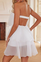 Back view of a woman in a white strapless tiered chiffon mini dress with an open back
