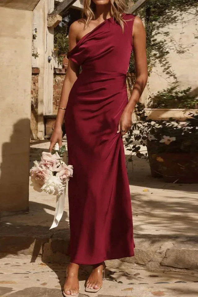 Woman wearing a floor-length burgundy satin one-shoulder dress with draped detailing.