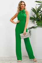Full body shot of a woman in a green wide leg halter neck jumpsuit