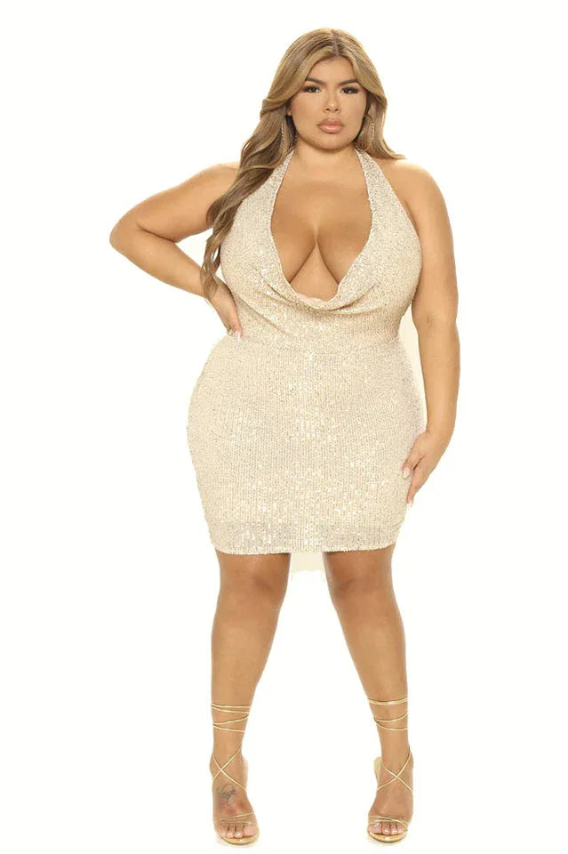 Woman in a champagne sequined halter dress with a cowl neckline and strappy heels.