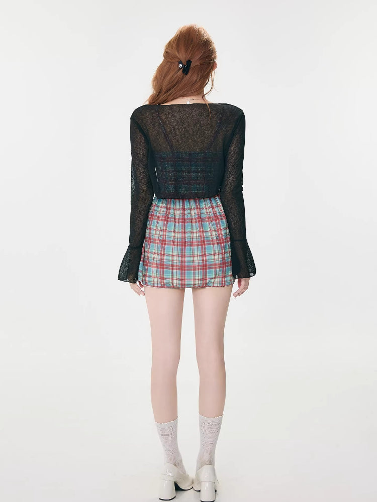 Back view of a woman wearing a black sheer bell sleeve cardigan and a red and blue plaid spaghetti strap mini dress.