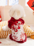 Back view of a white dog wearing a red and white traditional Chinese style dog jacket with floral and dragon embroidery and red faux fur trim.