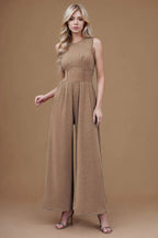 woman wearing a sleeveless wide leg jumpsuit in taupe