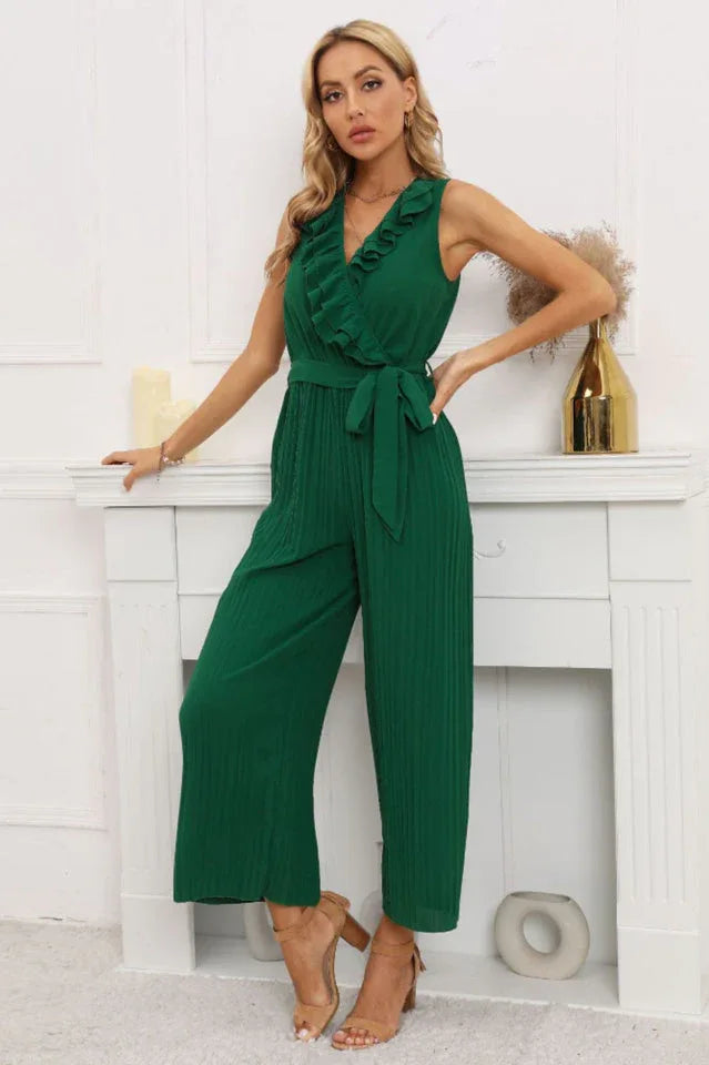 Woman in a green ruffled V-neck jumpsuit with pleated wide legs and a tie belt.