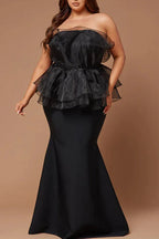 Plus-size woman in black strapless formal dress with ruffled organza peplum and mermaid skirt