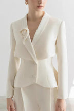 Close-up of ivory pantsuit jacket with V-neck and lapel flower accent
