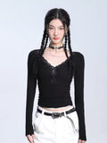 Woman wearing a black long-sleeve ribbed knit top with a V-neckline and lace trim, featuring a decorative bow and lace-up front detail.
