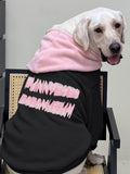 Side view of a Labrador Retriever dog in a black hooded sweatshirt with pink text.