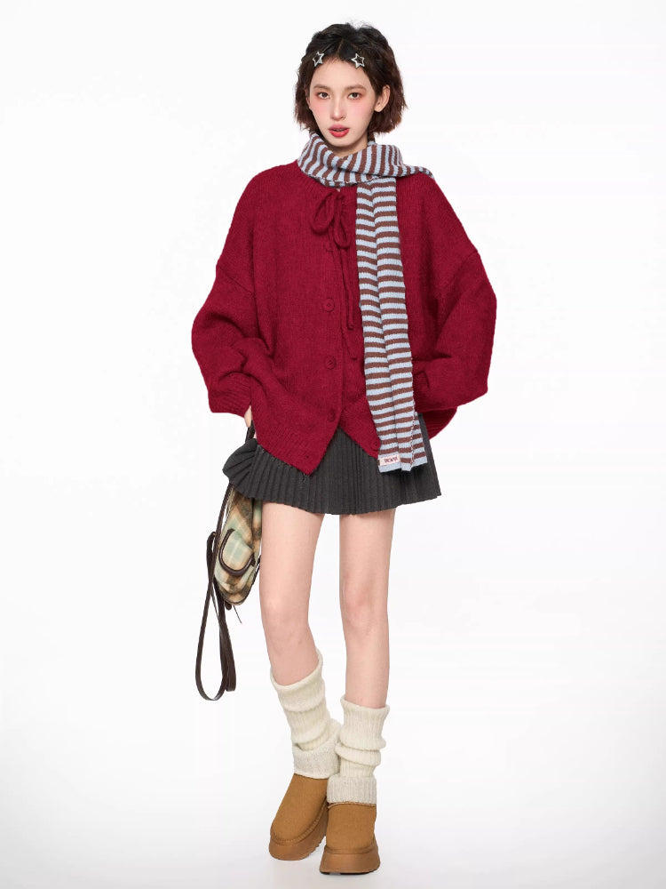 Woman wearing a red knit cardigan with a tie neckline and button closure, accessorized with a striped scarf.