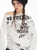 Detailed view of the graphic print on a white long-sleeve top with an off-the-shoulder neckline.
