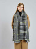 Woman wearing a black, white, and yellow plaid scarf with fringe detail.
