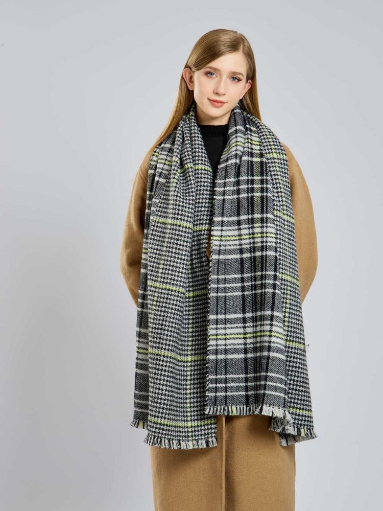 Woman wearing a black, white, and yellow plaid scarf with fringe detail.