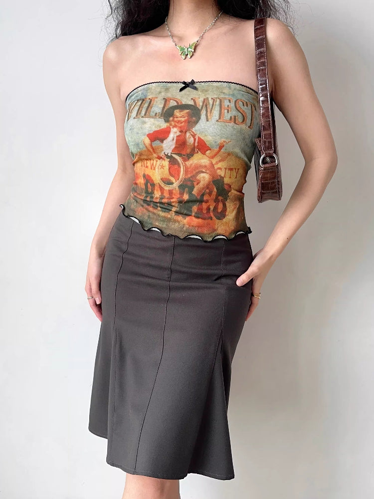 Full body shot of a woman wearing a graphic print tube top and a dark skirt.