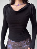 Woman wearing a black fitted long-sleeve top with a cowl neck and bow accents on the shoulders.