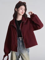 Woman in a maroon bomber jacket and jeans, showing the relaxed fit