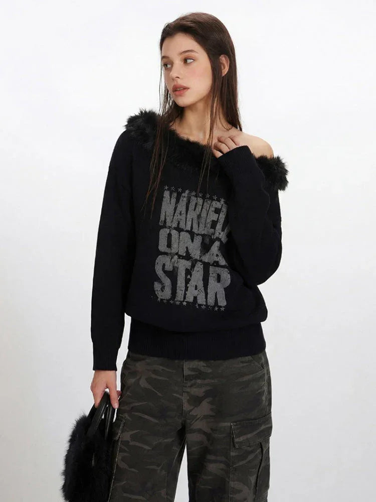 Close-up of a woman wearing a black off-the-shoulder knit sweater with faux fur detailing and a distressed graphic print.