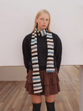 Woman wearing a striped knitted scarf with black, white, blue, and brown horizontal stripes