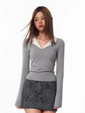 Woman wearing a grey long-sleeve top with a white contrast collar and a leopard print skirt.