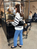 Woman in a striped knit sweater and blue jeans standing in front of a display case in a cafe.