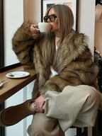 A woman enjoys a coffee break while wearing a stylish faux fur jacket.