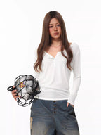 Woman wearing a white long-sleeve henley shirt and distressed wide-leg jeans