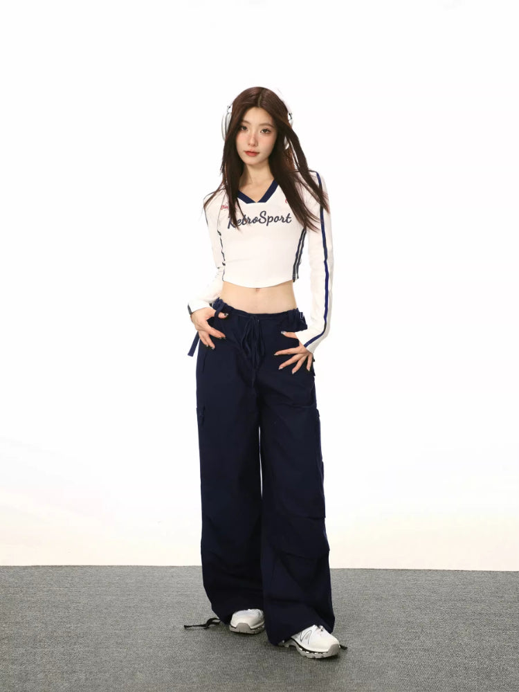 Model wearing a white long-sleeve crop top with 'RetroSport' graphic and navy trim.