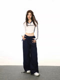 Full body shot of a model in a white long-sleeve crop top and navy cargo pants.