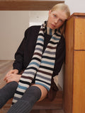 Woman leaning against wooden furniture with striped scarf