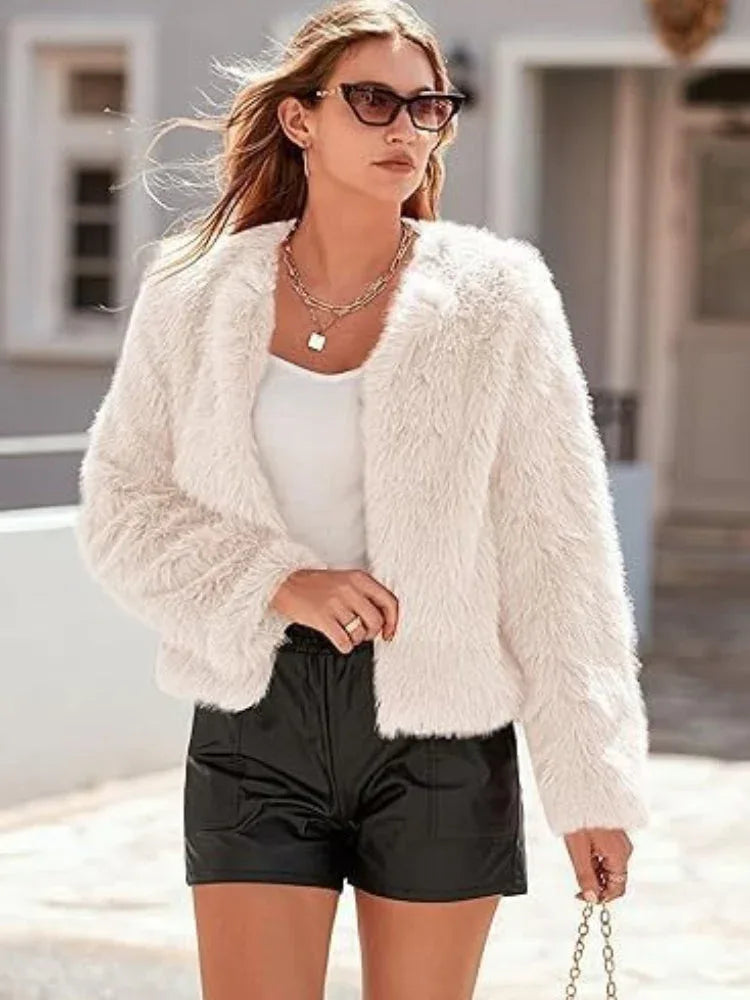 Woman wearing a white faux fur cropped jacket with black shorts.