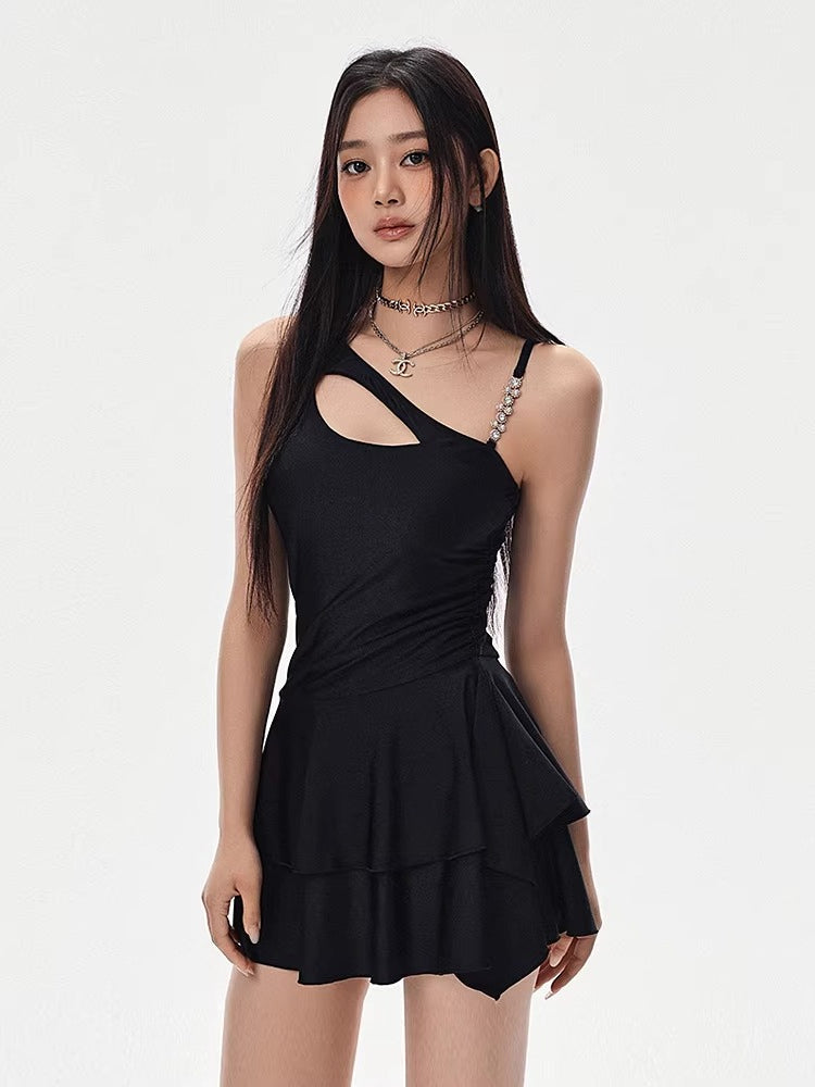 Woman wearing a black one-shoulder dress with a cut-out and tiered skirt