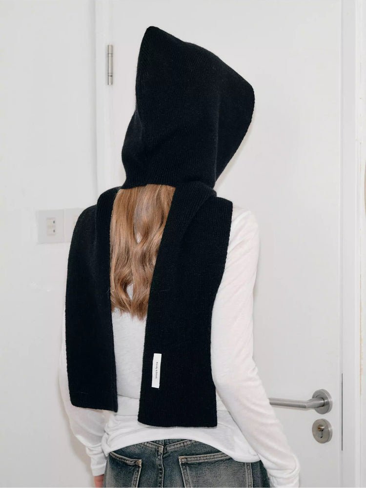 Back view of a woman wearing a black knit hooded scarf and white shirt