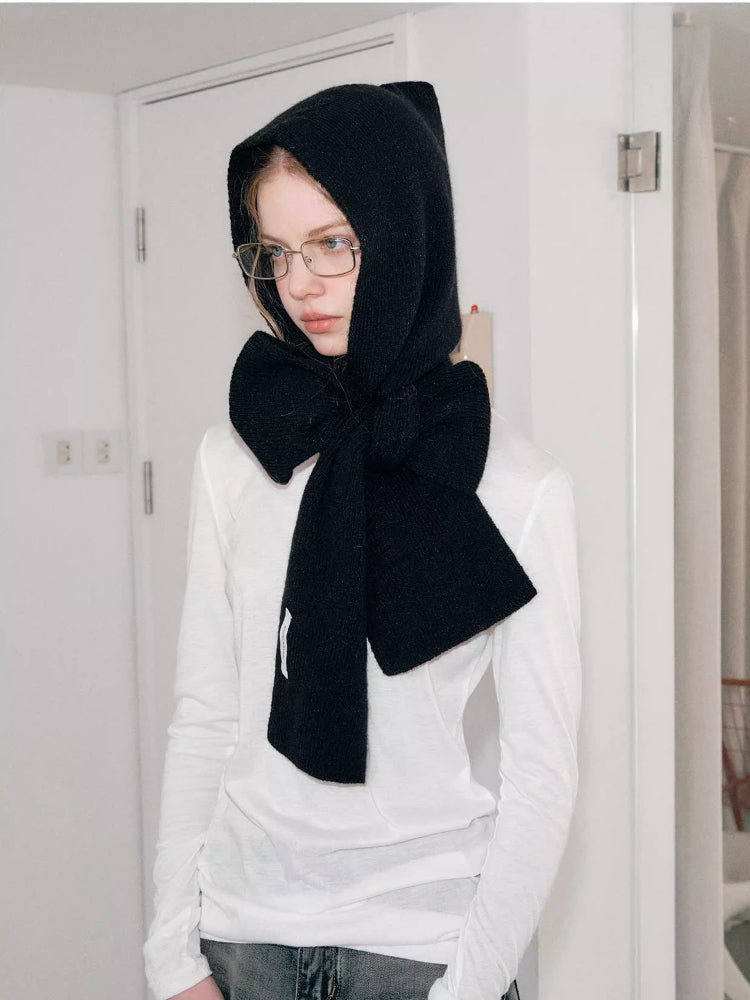 Woman wearing a black knit hooded scarf with a large bow detail