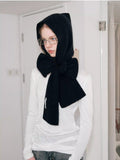 Woman wearing a black knit hooded scarf with a large bow detail